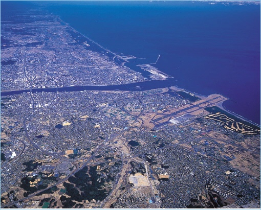 Aerial view of Miyazaki City, showcasing its coastal landscape, urban areas, and the Pacific Ocean nearby.