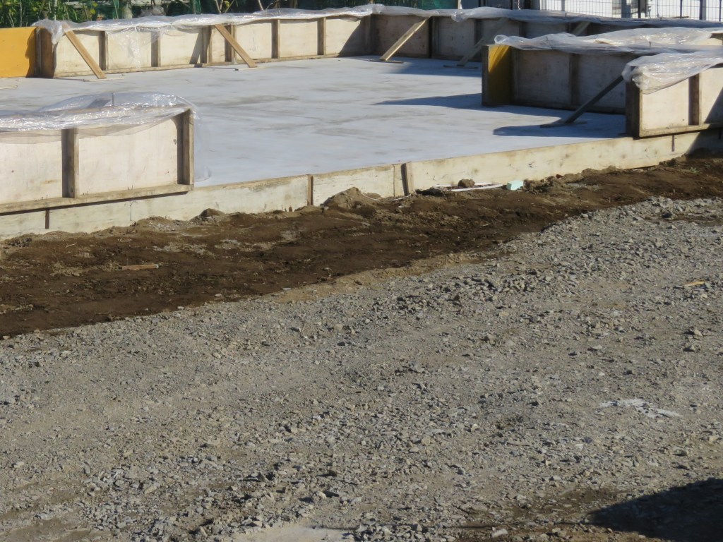 Construction site with a concrete foundation and wooden forms laid out for a building structure.