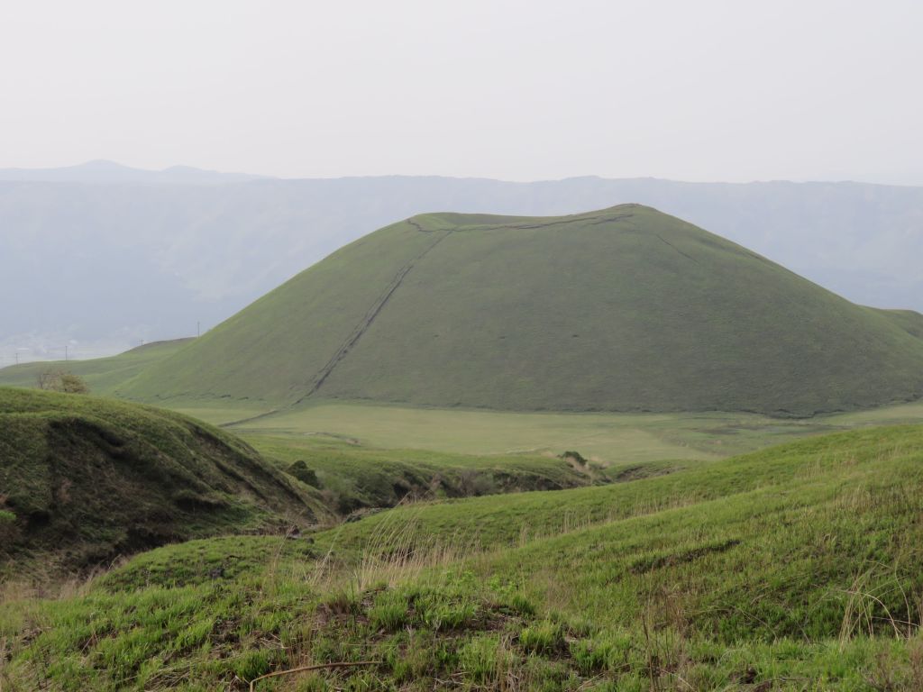 Lush green grass covering a volcanic hill in Aso, Kyushu, Japan, on a cloudy day.